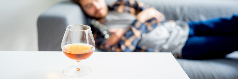 Alcohol and Sleep | Aeroflow Sleep Man sleeping on couch with a drink on the table